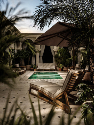 Patio with pool, lounge chairs, and palm trees.