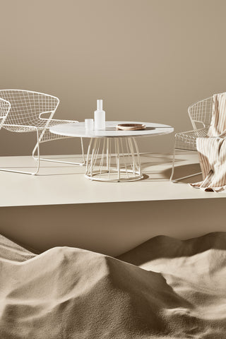 ND styled chairs and coffee table against a beige wall with sand at the base