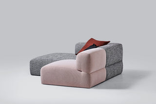 Modern pink and gray sectional sofa with a red pillow.