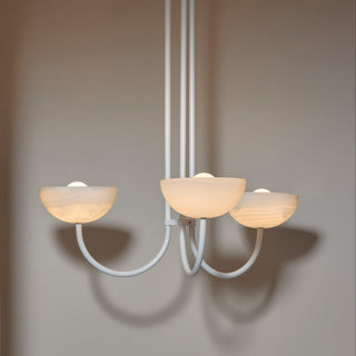 Modern chandelier with three glass shades against a neutral wall.