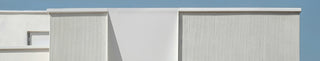 Modern building facade with white walls and a blue sky.
