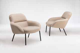 Two beige armchairs on black legs.