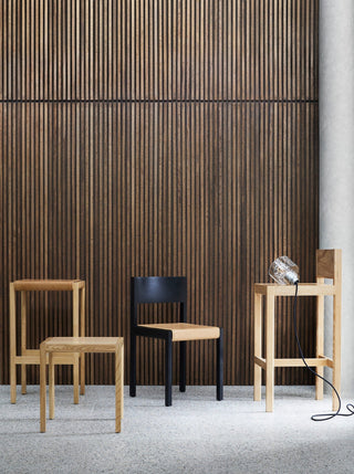 Wooden chairs in front of a slatted wood wall.