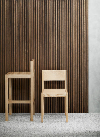 Two wooden chairs in front of a wood-slat wall.