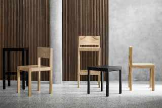 Wooden chairs and a small table against wood paneling.