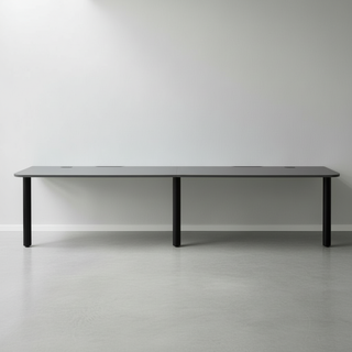 Long dark gray table with black legs on a light gray floor and white wall background