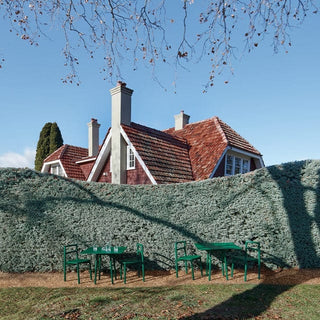 house with red roof, green tables & hedge