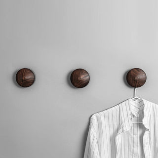 Three wooden wall hooks holding a shirt