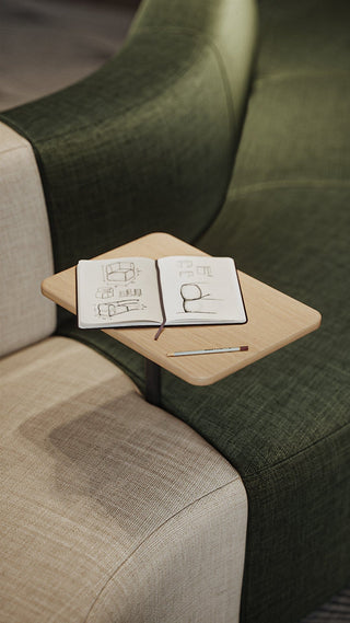 Notebook and pencil on a small table attached to a green couch.