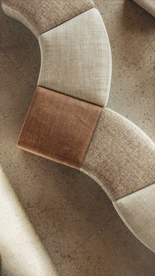 Curved sofa with neutral-toned fabric sections.