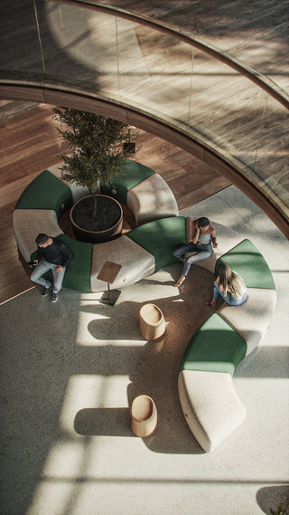 People sitting on green and white curved seating in an atrium.